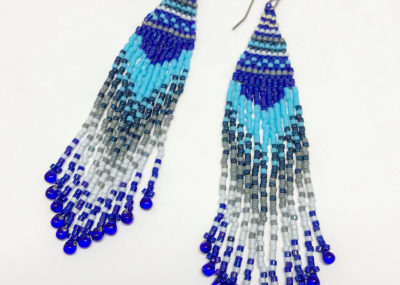 Wave of Blue Fringe Ombre Woven earrings on white background.